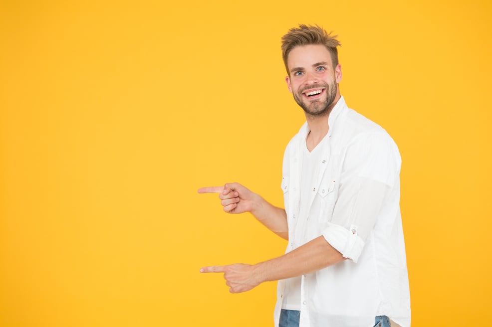 Look there. Man pointing at copy space. Check this out. Man muscular handsome smiling unshaven guy on yellow background pointing finger. Advertising concept. Summer advertising. Advertising agency